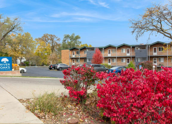 an apartment building with red flowers in front of a sidewalk at River Oaks, North Aurora, Illinois