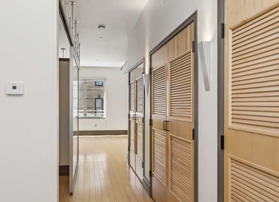 A hallway with wooden doors and a white wall.