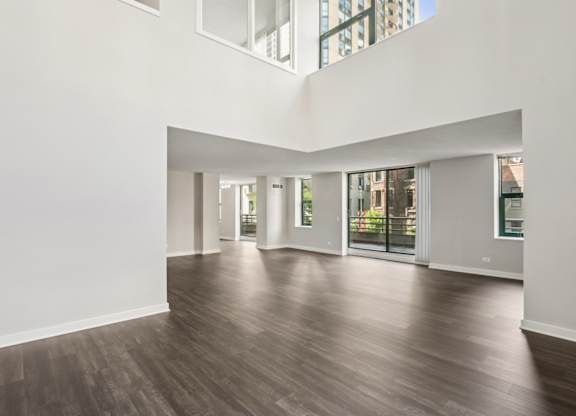 A spacious room with wooden floors and large windows.