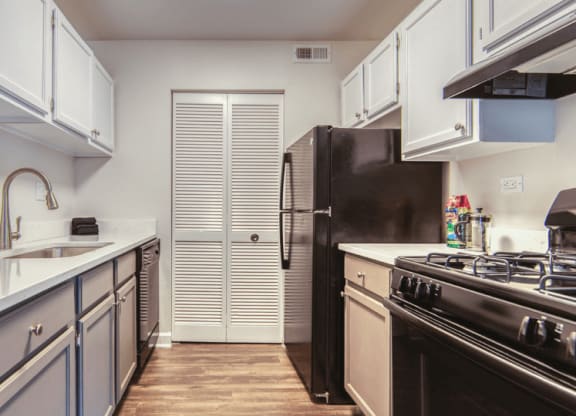 a kitchen with white cabinets and black appliances at The View Apartments St Charles, St Charles, IL