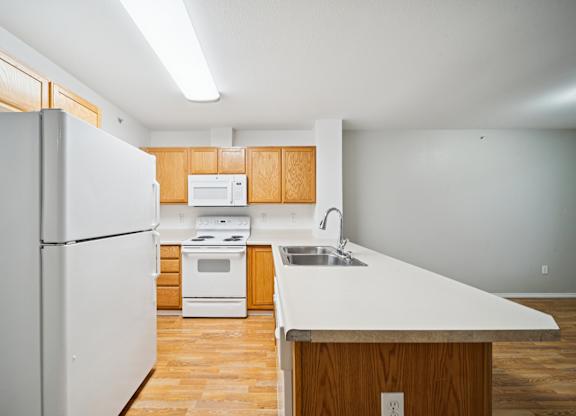 A white refrigerator is in a kitchen with wooden cabinets and a white counter top.