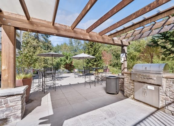 a patio with a grill and tables with umbrellas
