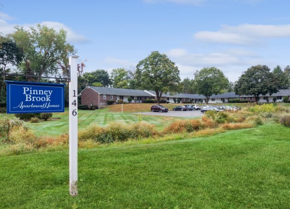 a blue and white sign in the grass in front of a building