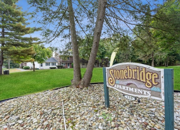 a sign for stonebridge apartments in front of a lawn and trees at Stonebridge, Ellington, CT