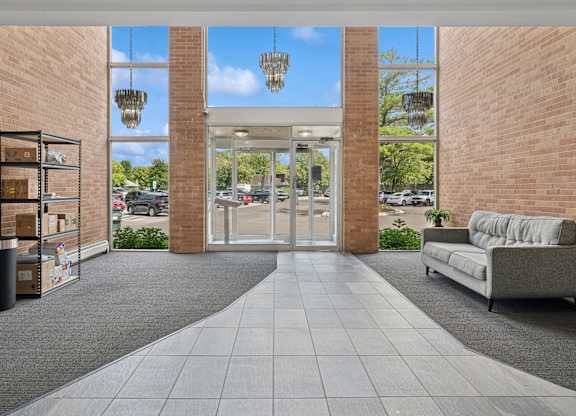 A modern building entrance with a glass door and a grey sofa.