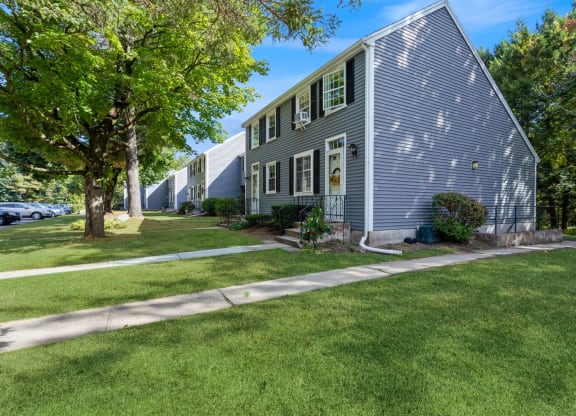 Exterior view of our apartments with a sidewalk and landscaping in front at Arbor Commons