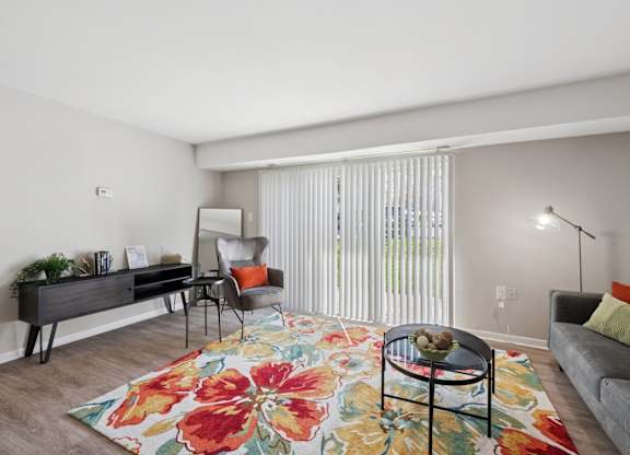 A living room with a floral rug and a grey couch.