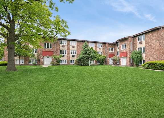 A grassy area in front of a brick apartment building.
