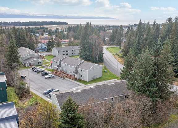 A large white building surrounded by trees and a parking lot.