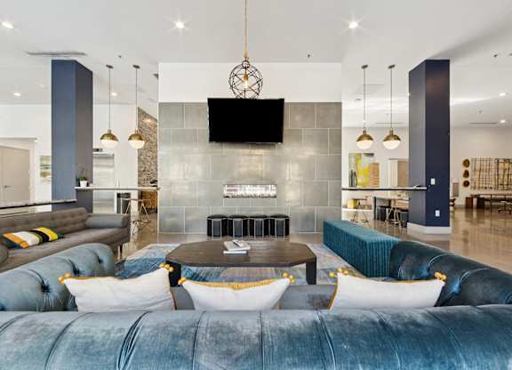 A modern living area with a blue velvet sofa and a television mounted on the wall.