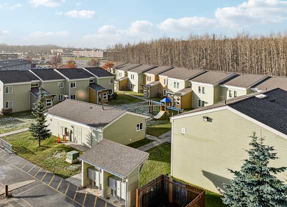 A row of houses with a tree in front of the first house.