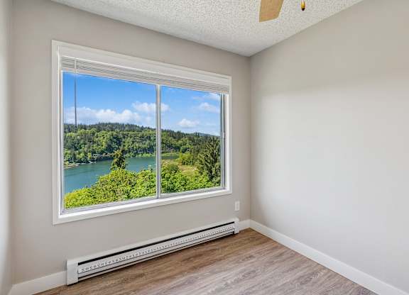 A room with a window overlooking a lake.