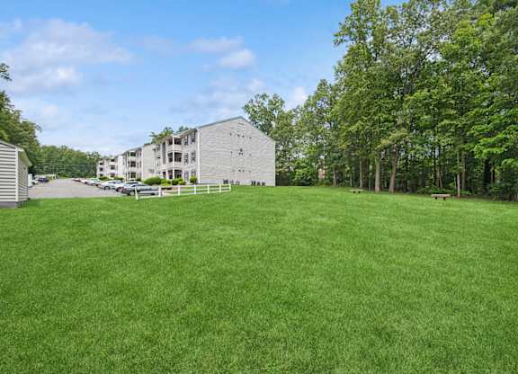A large grassy field with apartment buildings and trees in the background