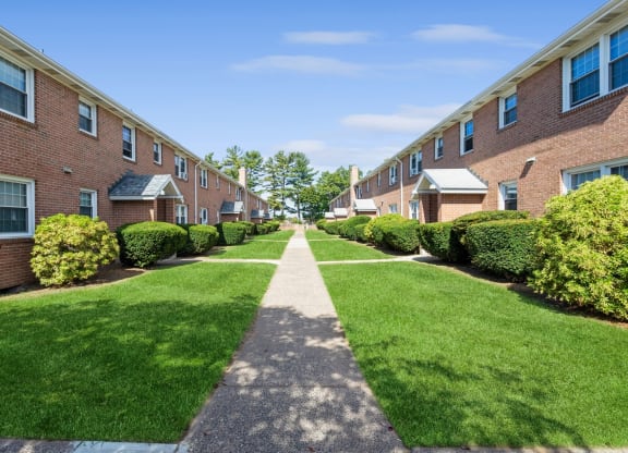 a walkway between two rows of brick apartment buildings