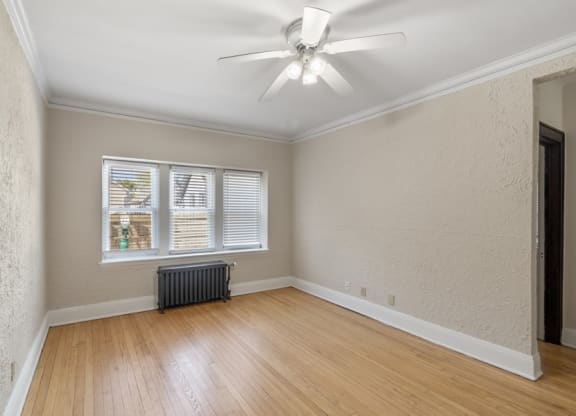 an empty living room with a ceiling fan and a window