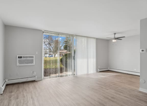 an empty living room with a sliding glass door to a balcony at The Reserve on Washington, Naperville