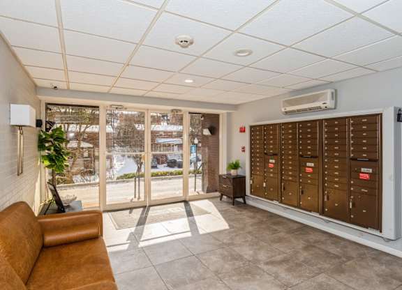 A room with a brown couch and a wall of mailboxes.