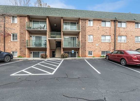 A parking lot in front of a brick apartment building.
