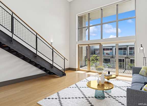 A living room with a staircase and a large window.