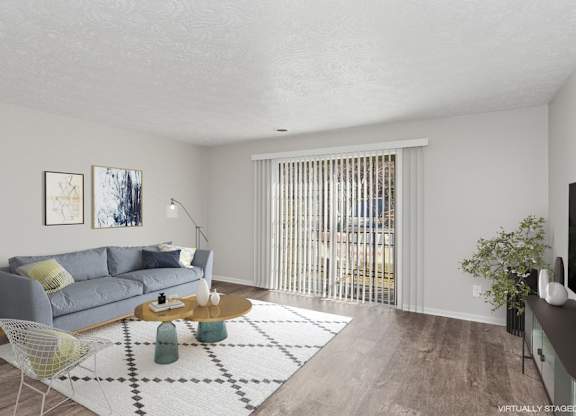A living room with a grey couch, a yellow chair, a coffee table, and a rug.