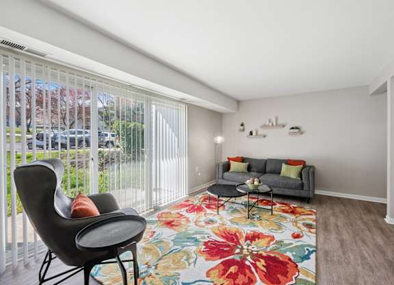 A living room with a grey couch, a black chair, and a floral rug.