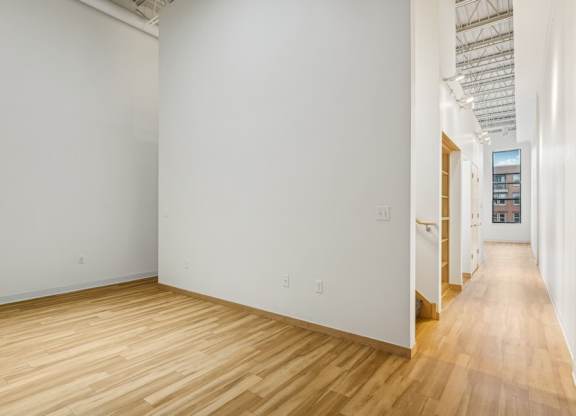A long hallway with wood floors and white walls.