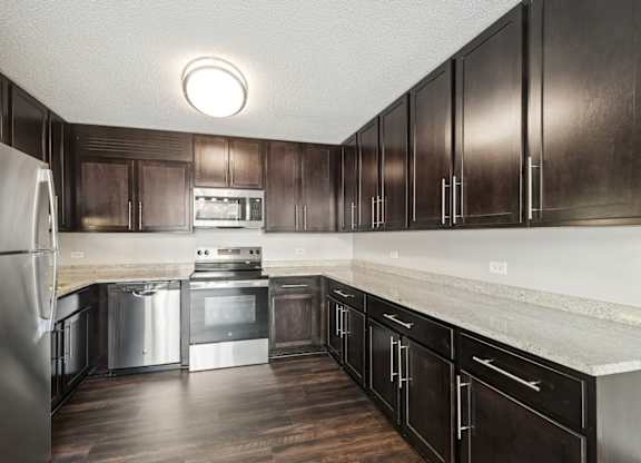 A kitchen with dark wood cabinets and stainless steel appliances.