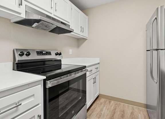 A kitchen with white cabinets and a black refrigerator.