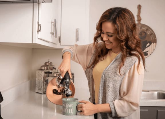 a woman pouring coffee into a mug in a kitchen at The Township at St. Charles, Illinois, 60174