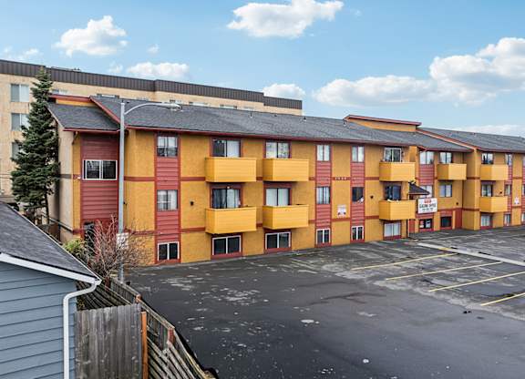 A parking lot in front of a row of apartment buildings.