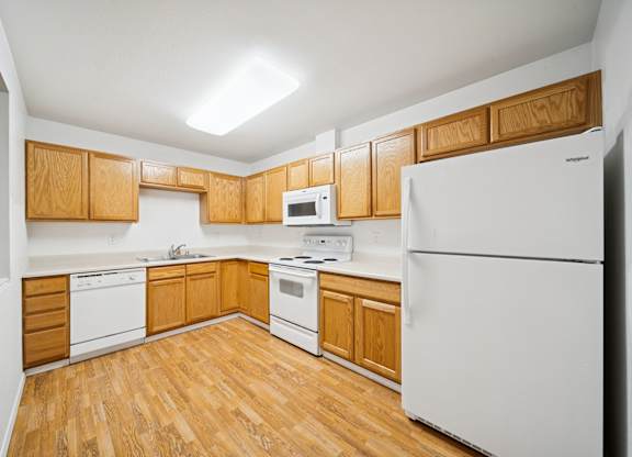A kitchen with wooden cabinets and white appliances.