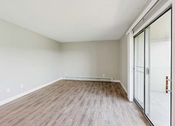 A room with a sliding glass door and wood flooring.