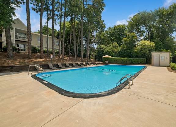 A small pool surrounded by trees and a building.