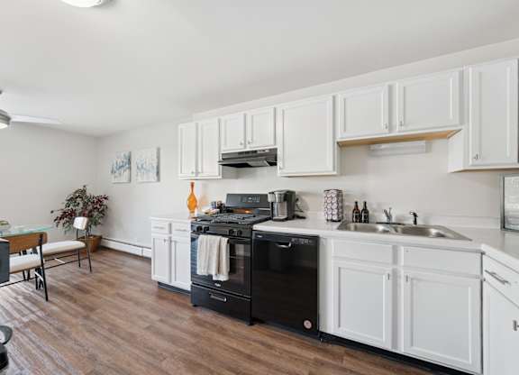 A kitchen with white cabinets and a black dishwasher.