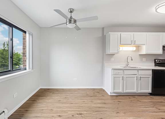 A kitchen with white cabinets and a ceiling fan.