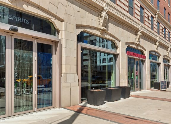 the facade of a building with large glass doors and a sidewalk at The Rowe, Grand Rapids, 49503