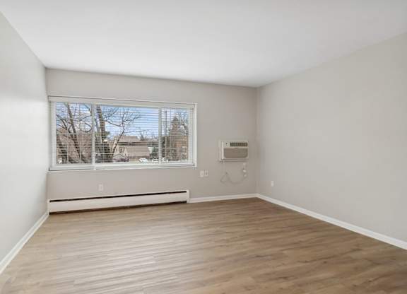 A room with a window and a wall-mounted air conditioner unit.