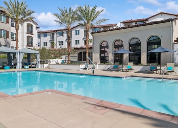 a swimming pool with chairs and umbrellas at Arrive Temecula