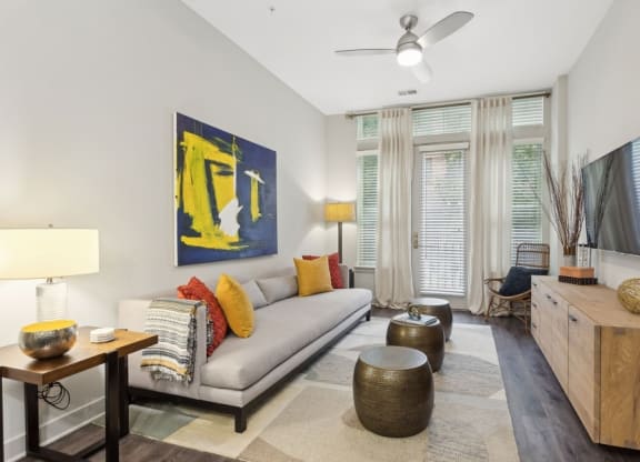 a living room with a gray couch and a yellow painting