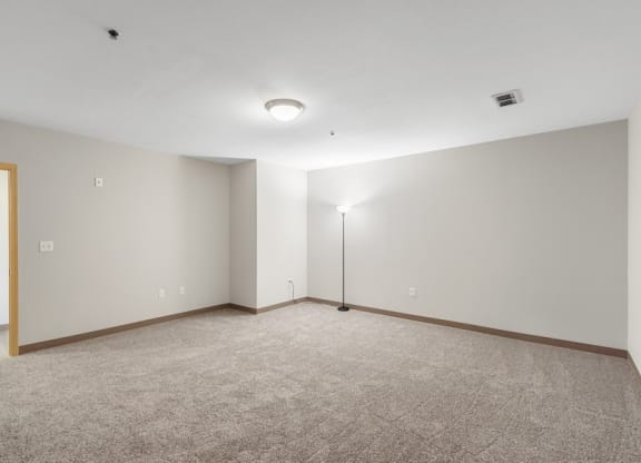 the living room of an empty apartment with carpet and a lamp