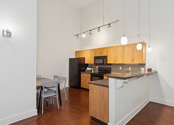A kitchen with wooden cabinets and a black fridge.