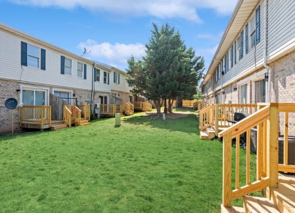 a backyard with green grass and a brick building with a tree in the middle at Fort Collier Terrace, Winchester, VA 22601