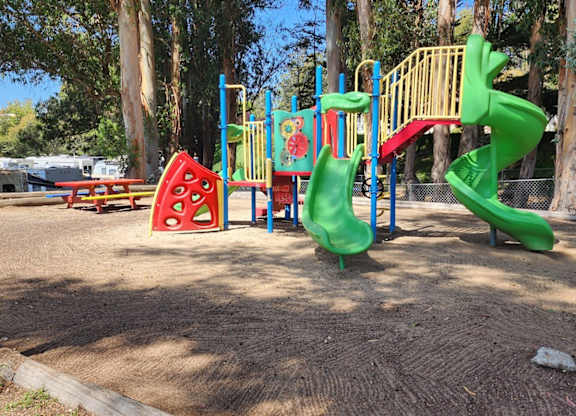 A playground with a green slide and a red and yellow climbing structure at Salinas Sunset Apartments, Salinas, CA