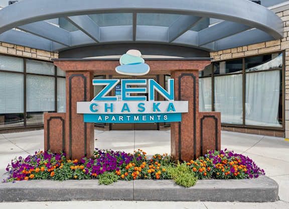 A Zen Chaska apartments sign is in front of a building.