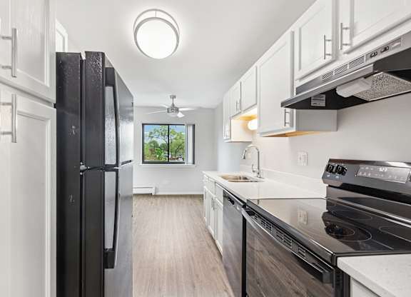 A modern kitchen with black appliances and white cabinets.