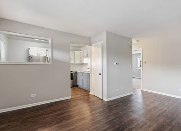a bedroom with a medium hardwood floor and a kitchen in the background at The Hinsdale, Hinsdale
