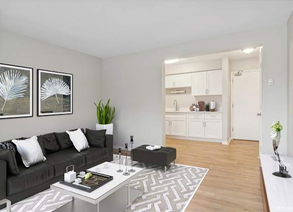 A modern living room with a grey sofa, a coffee table, and a TV on the wall.