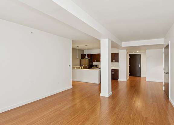 A spacious room with wooden floors and white walls.