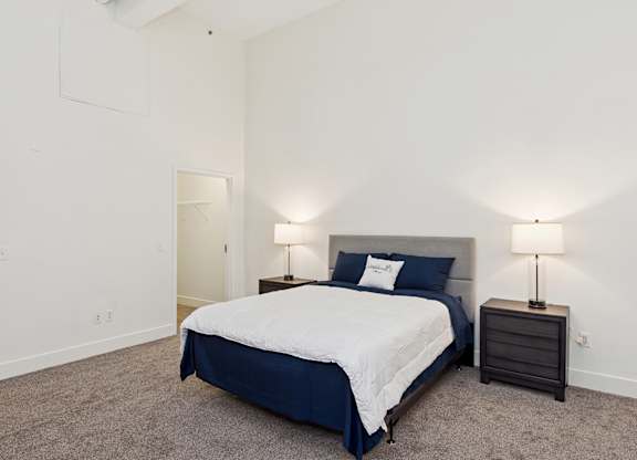 A bedroom with a bed, nightstand, and lamp.