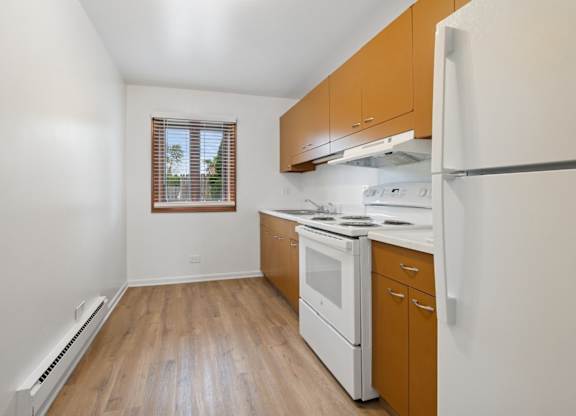 A kitchen with white appliances and wooden cabinets.